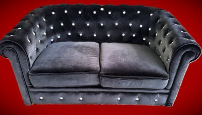 une photo d'un canapé Chesterfield en velours noir aux accoudoirs cloutés
