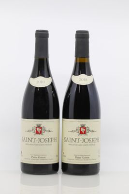 two bottles of red wine sitting next to each other on a white surface