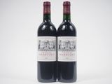 two bottles of red wine sitting next to each other on a white surface