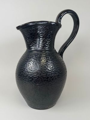 a black vase that is sitting on a white surface