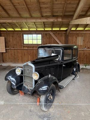 une vieille voiture noire dans un garage aux murs en bois