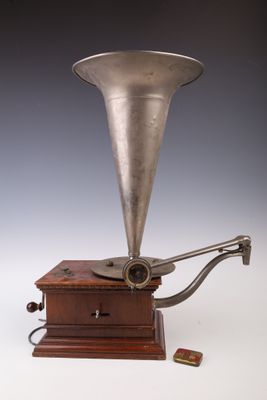un vieux gramophone plaqué argent posé sur un socle en bois, avec un fond noir