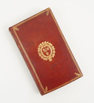 un vieux livre orné d'un emblème doré posé sur une surface blanche