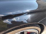 a close up of a car ' s rear end with a reflection of a building in the window