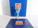 une petite figurine représentant un homme debout devant un livre bleu
