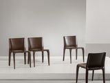 Trois fauteuils en cuir marron sont disposés sur une estrade blanche dans une pièce blanche