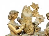 a gold clock with a woman and a bird on it