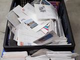 a black basket full of mail sitting on the floor