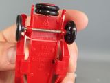 a person holding a red toy car in their hand