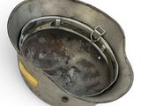 a metal pan with a yellow handle on a white surface
