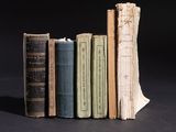 several old books are stacked on top of each other on a black surface
