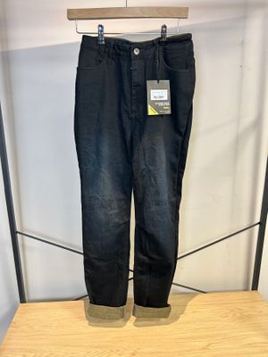 Le jean noir est suspendu à un cintre sur une étagère en bois.