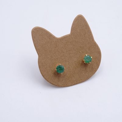 boucles d'oreilles en forme d'oreilles de chat ornées de pierres vertes, posées sur un carton