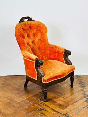 une chaise orange posée sur un parquet, près d'un mur blanc