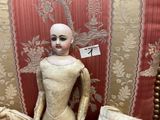 a doll that is sitting on a chair in front of a wall