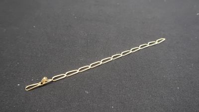 a close up of a gold chain bracelet on a black surface
