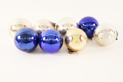 several blue and silver christmas ornaments on a white surface