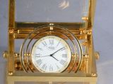 une horloge en or posée dans une vitrine, sur un support blanc