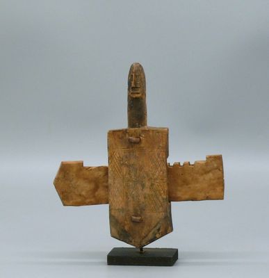 une vieille sculpture en bois représentant un homme tenant un couteau, posée sur un socle