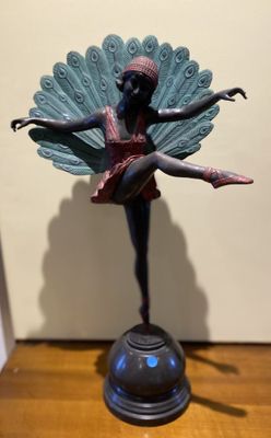statue of a ballerina with a peacock tail on a wooden table