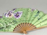 un éventail vert orné de fleurs violettes et blanches