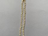 a close up of a gold beaded necklace on a gray surface