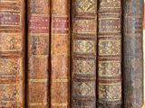 several old books are lined up on a shelf in a library