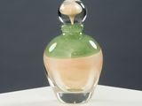 a glass bottle with a green liquid inside on a white surface