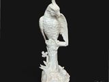 une statue blanche représentant un oiseau perché sur une souche d'arbre