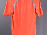 a close up of an orange shirt hanging on a hanger