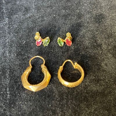 two pairs of gold earrings with colorful stones on a black surface