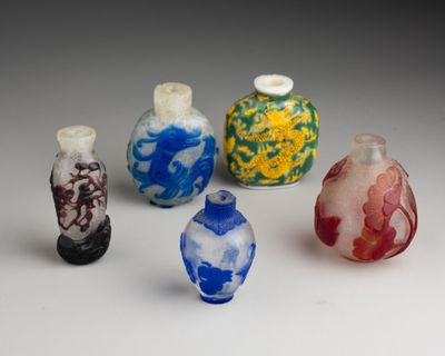 Plusieurs petits vases en verre sont alignés sur une surface blanche