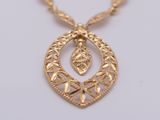 a close up of a gold necklace with a leaf design on it