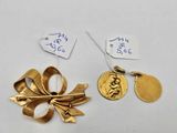 two pieces of gold jewelry with tags on them on a white surface