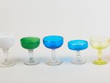 several different colored wine glasses are lined up on a white surface