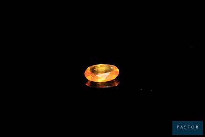 an orange sapphire in the dark with a black background