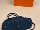 a blue handbag next to an orange box on a white surface