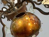 a vase hanging from a chandelier with a plant in it