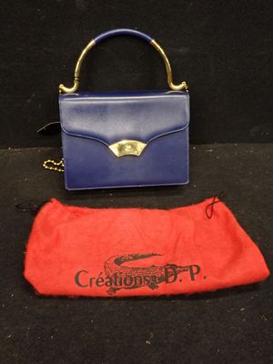 un sac à main violet et bleu et une pochette rouge posés sur un fond noir