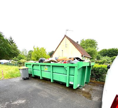 a green dumpster sitting in the middle of the road