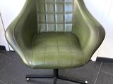 fauteuil pivotant en cuir vert, avec des pieds en métal noir et un piètement noir