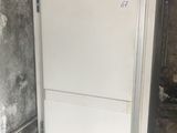 a white refrigerator in the corner of a dirty room