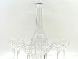 cinq verres à vin et une carafe posés sur une table