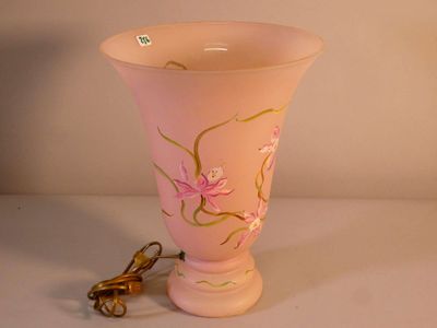 un vase rose avec une anse dorée posé sur une table blanche