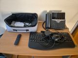 une photo d'un bureau sur lequel se trouvent un clavier, un téléphone et un sac