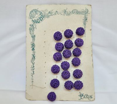 des boutons violets au crochet posés sur un morceau de papier bordé de vert