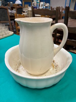 a white pitcher sitting on top of a bowl on a table