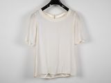 a white t - shirt hanging on a hanger against a white wall
