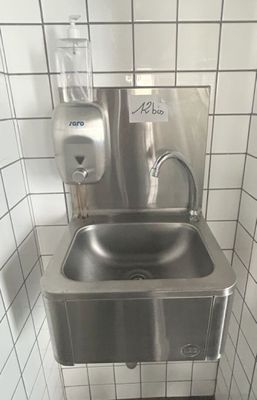 un évier en acier inoxydable dans le coin d'une toilette publique