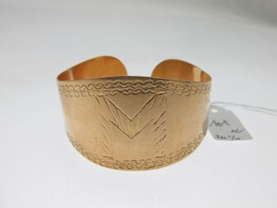 un gros plan d'un bracelet manchette en or orné d'un motif